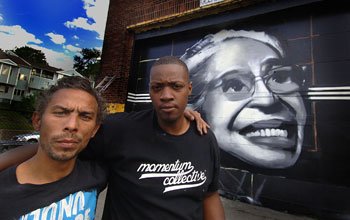 Cedric Douglas (L) and Percy Fortini-Wright pause for the camera after finishing their mural of civil rights icon Rosa Parks earlier this month. The two were part of Mural Fest, which brought together over 80 Boston artists to transform a deserted parcel of land just outside of Dudley Square in Roxbury into the largest public art event and collection of street art in the history of the city.