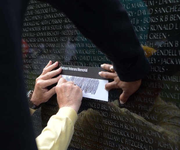A volunteer traces a name at the Vietnam Memorial on Monday, May 27, 2013.