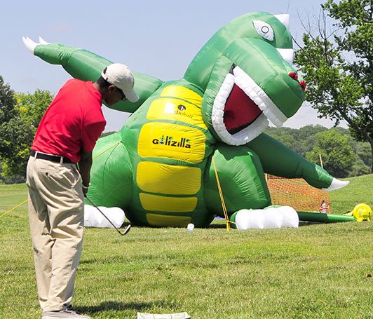 A golfer tries his luck at hitting a golf ball into the mouth of a blow-up Godzilla at the Langston Golf Heritage Celebration in Northeast on Saturday, June 8.