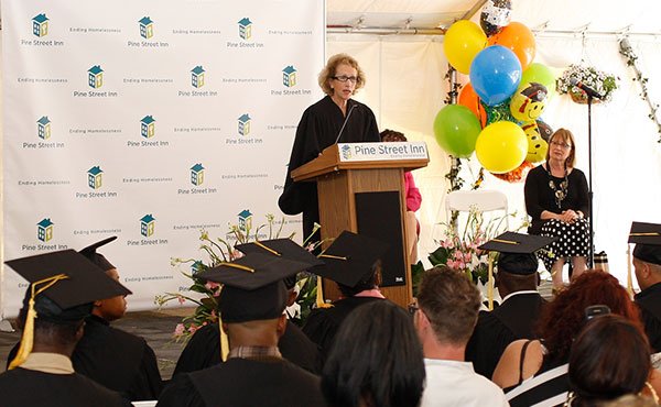 Graduates from Pine Street Inn’s job training program listen to speakers during a recent graduation ceremony. The graduates, all homeless men and women, ranging in age from 20s to 60s, wore caps and gowns to celebrate the completion of the program, which featured training in food services, building maintenance and housekeeping.