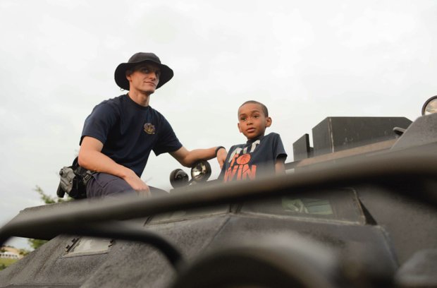 Joshua Jamieson, 8, talks with Officer Matt Jordan, a member of the Laurel, Md., Police Department SWAT team, atop an armored vehicle at the town's annual National Night Out in Granville Gude Park on Tuesday, Aug. 6. The yearly event gives Laurel's law enforcement and rescue personnel an opportunity to meet with the community.