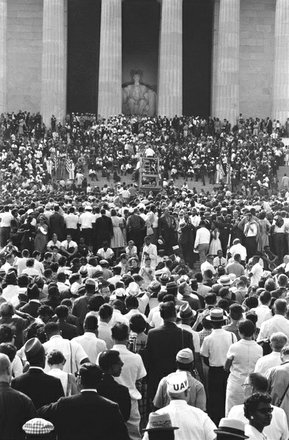 The large crowd of people wait and watch for speakers.