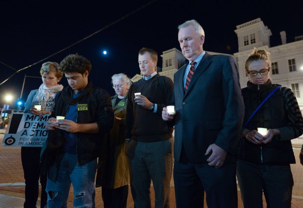 D.C. Council member Tommy Wells (center), Ward 6 Democrat, asks for a moment of silence during a candlelight vigil for the victims of the Washington Navy Yard shooting at 8th and M streets in Southeast on Tuesday, Sept. 17.