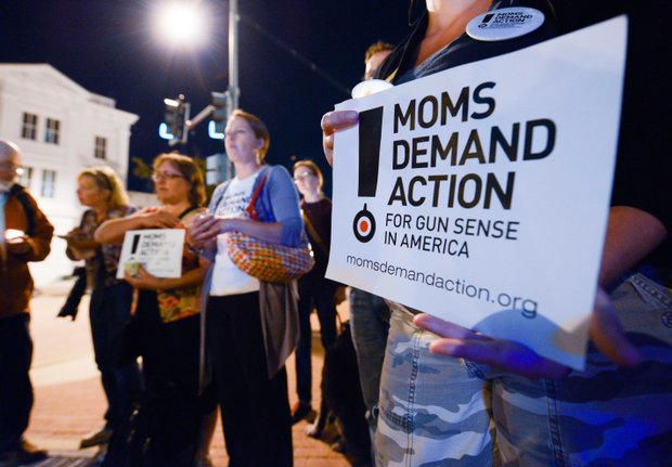 Gun-control advocates hold signs at a candlelight vigil for the victims of the Washington Navy Yard shooting at 8th and M streets in Southeast on Tuesday, Sept. 17.