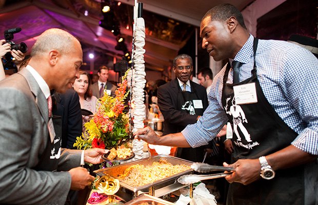 Former New England Patriots player Eric Alexander serves food from Darryl’s Corner Bar and Kitchen to Gov. Deval Patrick at the 16th “Men of Boston Cook for Women’s Health” at the Codman Square Health Center on Sept. 26.