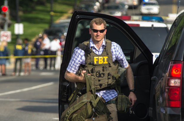 An FBI agent helps secure the scene Thursday afternoon after a woman was shot to death following a high-speed chase on Capitol Hill. The White House and U.S. Capitol were temporarily shut down during the incident.