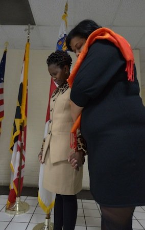 Global Vision Community Health Center founder Toyin Opesanmi (left) and an unidentified woman pray during the grand opening of the health center in Capitol Heights, Md., on Thursday, March 6.
