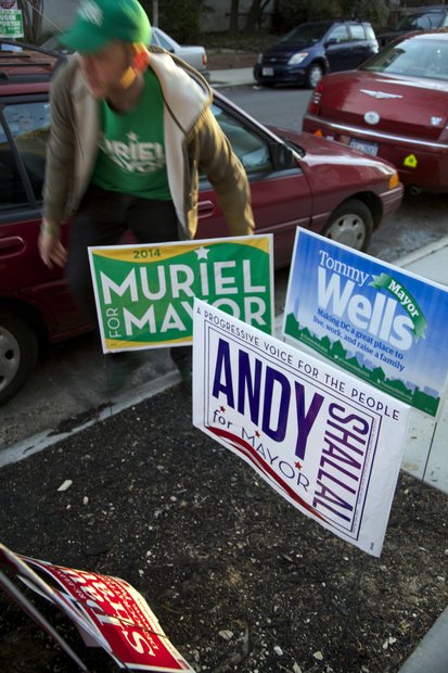 Matthew Santoro, 29, quickly posts campaign signs for mayoral candidate Muriel Bowser after the polls opened on Primary Day in Northwest. /Photo by Nancy Shia
