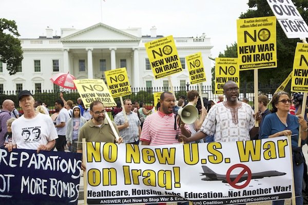 From left: David Barrows, Sunil Freeman, Eugene Puryear (with megaphone), Akufuna Ngonda, and Elizabeth Loweng stand behind banners in front of the White House on June 21 during a demonstration against new military action in Iraq.