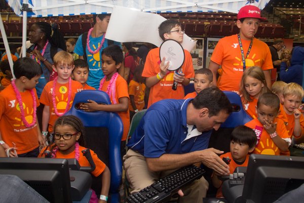 Chris Marchioni of the Air Force Academy helps children with flight simulation activities during the Thingamajig Conference hosted by the YMCA of Metropolitan Washington at Show Place Arena in Upper Marlboro, Md., on Thurs., July 24.