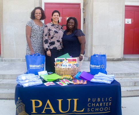 Paul PCS Middle School Principal Danielle Singh (left), Walmart Director of Community Affairs Nina Albert (center), and Paul PCS International High School Principal Kenya Wilson (right) at the table displaying donated classroom supplies in front of the charter school in Northwest on Monday, July 28.
