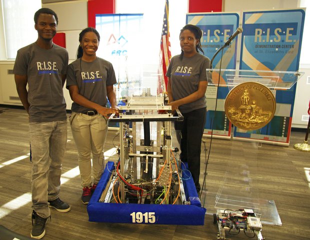McKinley Tech High School students (left to right) Cabrel Foyet-Fokov, 17, J’Niya Butler, 15 and Angel Collins, 15 at the grand opening of R.I.S.E. Demonstration Center located at St. Elizabeths East August 13, display the robot they built.