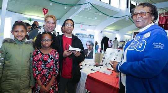 Member of Zeta Phi Beta Sorority, Inc., Dorothy McCormick with the Beckman and Williams family at the "Astronaut Suit" - Patricia Cowings station.