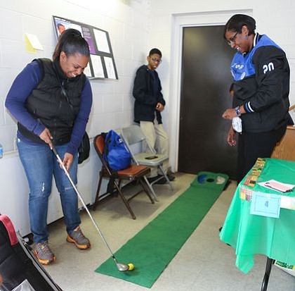 Member of Zeta Phi Beta Sorority, Inc., with attendee playing a hole in one at the "Golf Tee" - Dr. George Grant and David M. Bondu, Sr. station. -- Photo by April A. Ward