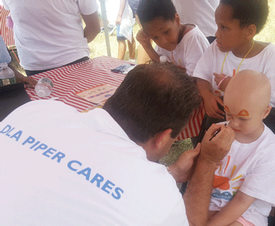 Baltimore partner Tom Pilkerton paints a camper’s face as others wait in line.