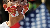 Wearing stickers on his face, an advocate attends “Rally for the American Dream – Equal Education Rights for All” in Boston ahead of the start of Monday’s court hearing in the lawsuit accusing Harvard University of discriminating against Asian-American student applicants.