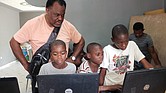 Mr. Barney watches as Haitian youths use the laptops he took to Pignon.
