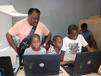 Mr. Barney watches as Haitian youths use the laptops he took to Pignon.