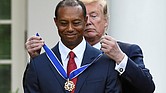 Golf champion Tiger Woods stands tall as President Trump places the Presidential Medal of Freedom around his neck during a ceremony Monday in the White House Rose Garden.