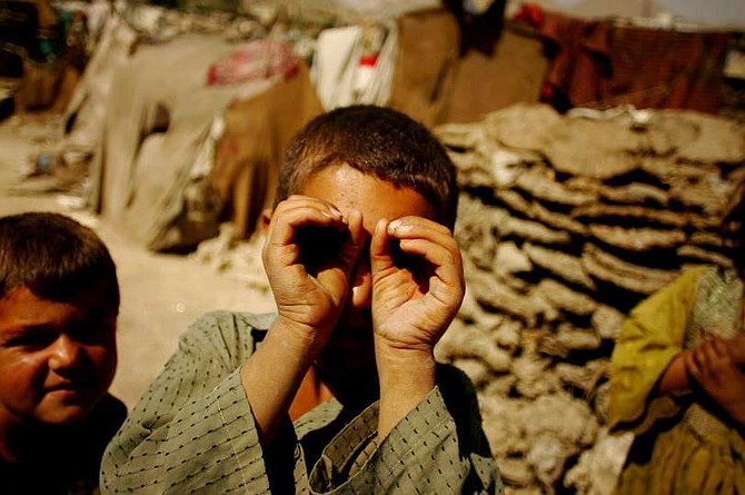 A boy gestures for a photographer in Internally Displaced Persons (IDPs) camp in Kabul, Afghanistan on August 28, 2009.