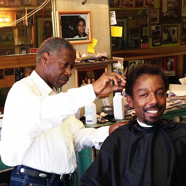 El-Hajj Elshabazz, who is being honored as a long-time barber, cuts his son, Damon Williams' hair. Williams also is a barbar at Truth and Soul Black Stars shop, 1740 E. 87th Street.