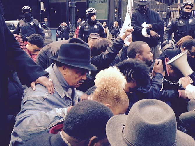 The Rev.Jesse Jackson Sr. and others marched Sunday on State Street in Downtown Chicago to protest against the shooting of a black teen killed by a white Chicago police officer. Jackson and others stopped to kneel to pray for justice.