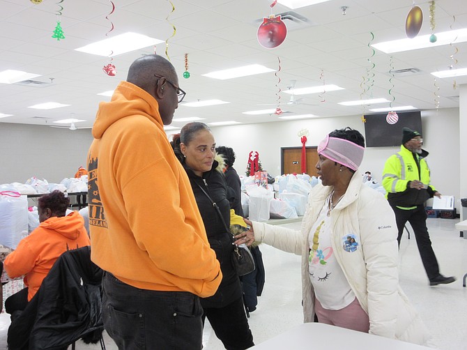 Roseland Ceasefire CEO, Bob Johnson (L) talks with two mothers whose adult sons were killed by gun violence, Kim Blackmon (C) and Paula Ward (R). The mothers say the annual holiday toy and food giveaway is something they look forward to, because it allows them to share their grief with others who understand what they are experiencing during the holiday season.