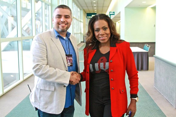 Celebrity host Sheryl Lee Ralph who is joined by West Coast Expo's Jose Torres, shows off one of the diva T-shirts she designed and sells to raise money to fight HIV/AIDS.