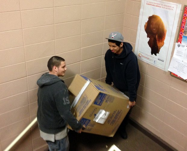 Alex Barrera (left) and Oscar Torres carry a box of food up to the Food Pantry at the Spanish Community Center in Joliet.