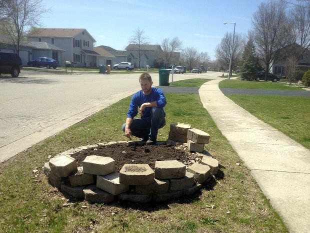 Jim Tieber, forester for Joliet, kneels over some dirt along a parkway in the Grand Prairie subdivision where an Ash tree was recently removed due to devastation from the Emerald Ash Borer.
