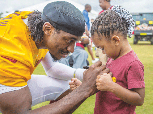 To this youngster's delight, Washington quarterback Robert Griffin III signs Destani Bailey's jersey Saturday during Fan Appreciation Dy at the teams's training camp in Richmond.  The team will hold its final practice at the facility Monday, Aug. 11.  Location:  2401 W. Leigh St.
