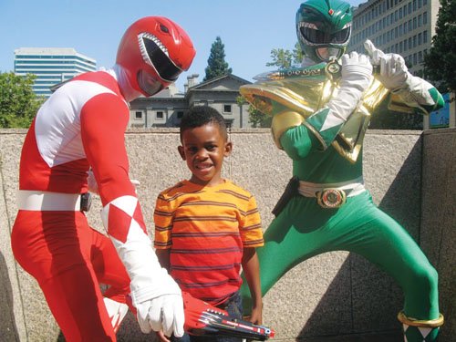 Five-year-old Savion Patterson poses with the Red and Green Power Rangers, played by Ash Naimi and Edward Estoy. The two men are known for playing popular cartoon and comic characters for events around town.