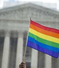 A same-sex marriage supporter waves a rainbow flag in front of the U.S. Supreme Court.