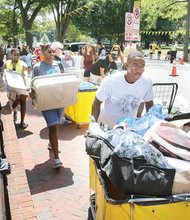 Stephen Guyton pushes his belongings toward his new home — a high-rise dorm at Virginia Commonwealth University. His mom, Valerie, and his sister, Taylor, follow with more items the Fredericksburg freshman brought with him. Location: Franklin Street near Monroe Park.  