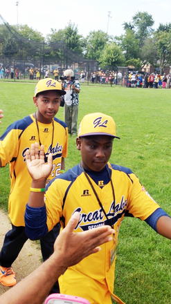 Jackie Robinson West Little League teammates, Darion Radcliff (front) and Prentiss Luster, gives “high fives” to fans at Jackie Robinson Park, 10540 S. Morgan Park St., as they head to board trolley buses for a parade for the team that ended at Millennium Park in downtown Chicago for a citywide celebration after becoming Little League Baseball’s 2014 World Series U.S. Champions. 