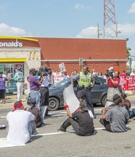 Fast food workers stage a sit-in on Mechanicsville Turnpike in front of the McDonald’s. Their purpose: To highlight their demand for a hike in the $7.25 minimum wage. Fellow activists on the sidewalk hold up signs of support.