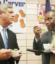 U.S. Secretary of Agriculture Thomas J. Vilsack, left, and Richmond Schools Superintendent Dana T. Bedden converse while eating broccoli Monday at Carver Elementary School.