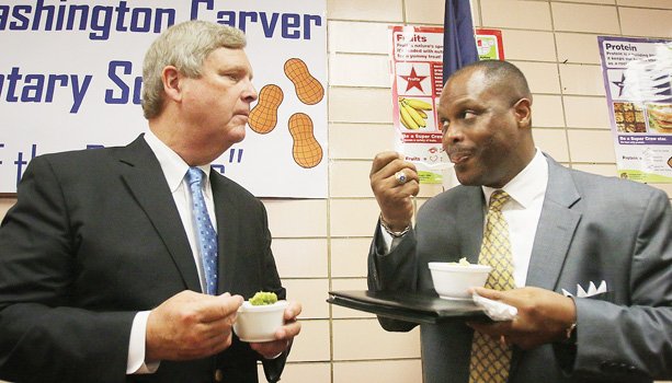 U.S. Secretary of Agriculture Thomas J. Vilsack, left, and Richmond Schools Superintendent Dana T. Bedden converse while eating broccoli Monday at Carver Elementary School.