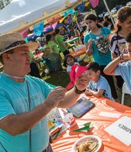 Andrės Valverde makes an oragami bird for 10 year old Cosme Salazar at the 2014 Imagine Festival.