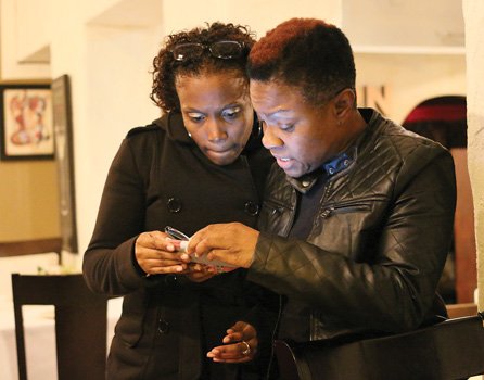 Radio personality “Miss Community” Clovia Lawrence, right, and Ebony Leach peruse poll results Tuesday night at an election night gathering at Southern Kitchen in Shockoe Bottom. 