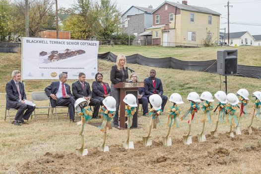 City Councilwoman Reva M. Trammell speaks glowingly about the 18 senior cottages planned for this site in the 400 block of East 15th Street in Blackwell. Among the dignitaries waiting to don hard hats and ceremoniously break ground are, from left, Richmond development chief Lee Downey, Congressman Robert C. “Bobby” Scott, RRHA Chairman Samuel Young, RRHA CEO Adrienne Goolsby, Richmond HUD office director Carrie Schmidt and building contractor Ray Miles.  