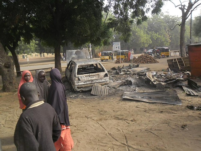 Children stand near the scene of an explosion in a mobile phone market in Potiskum, Nigeria, Monday Jan. 12, 2015. Two female suicide bombers targeted the busy marketplace on Sunday. (AP Photo/Adamu Adamu) 
