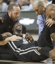 Virginia Commonwealth University basketball star Briante Weber grimaces as coach Shaka Smart, second from right, and others assist him moments after his injury during Saturday’s game against the University of Richmond at the Siegel Center.