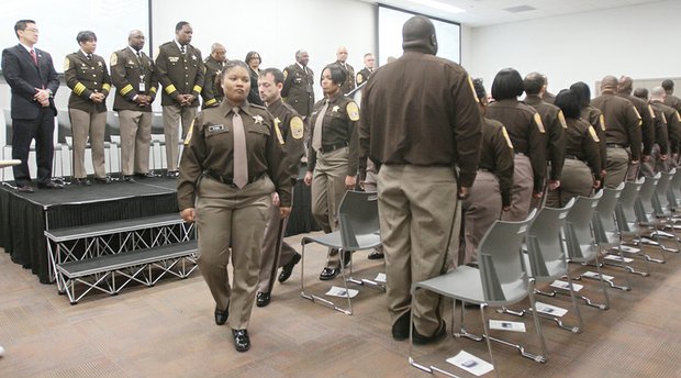 Jay’Neka Stancel proudly is pinned with a deputy’s badge by her father, Carl White, at the Richmond Sheriff Office’s first Basic Training Academy graduation ceremony last Friday at the new Richmond Justice Center. Class President Misha Goins leads her 22 classmates during the ceremony as Sheriff C.T. Woody Jr. and others watch from the stage.