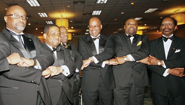 members of the Beta Gamma Lambda Chapter of Alpha Phi Alpha Fraternity clasp hands as
they are about to sing their fraternity song Saturday night at the organization’s 2015 Black and Gold Ball at
a Richmond area hotel.