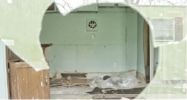 A view through a trailer’s broken window shows the destruction inside.