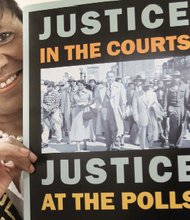Rita Willis of Henrico County displays the poster she brought back to Richmond after marching across the Edmund Pettus Bridge in Selma, Ala., Sunday to commemorate the 50th anniversary of “Bloody Sunday.”