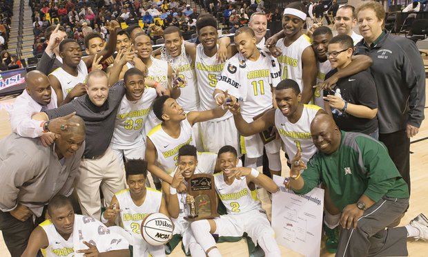 Team members and coaches celebrate and hold up two fingers, signaling their second state title in the past three years.