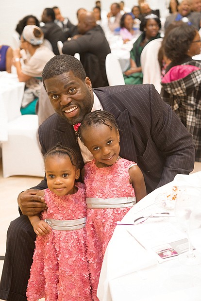 Robert W. Brown Jr. shares a treasured moment Sunday with his daughters, Kendell, 2, and Morgan, 4, at the Trinity Family Life Center on North Side.