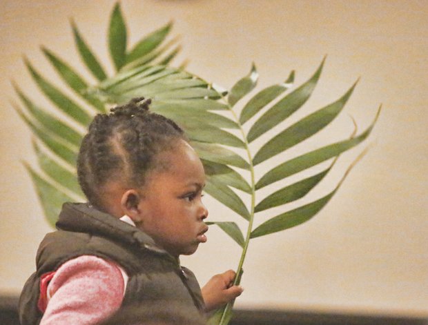 Nyjah Caleb, 2, holds a palm frond at East End Fellowship’s Palm Sunday worship service in Church Hill. She and others waved their palms to symbolize the palm branches the crowd scattered in front of Jesus as he rode into Jerusalem a few days before his crucifixion and resurrection that Christians will celebrate this weekend.